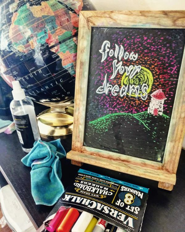 Chalkboard: Follow your dreams, with a rainbow sky over a hill.