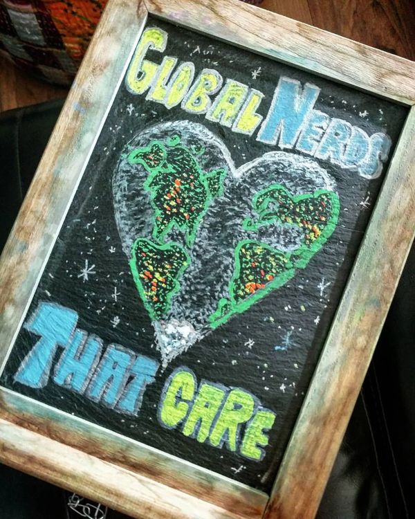Chalkboard: Global Nerds That Care, with a heart-shaped world map.