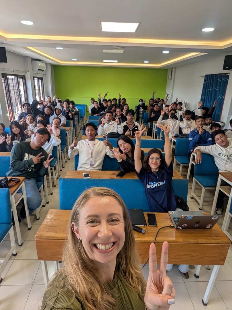 Claire taking a peace-sign selfie with a classroom of cheering students in Nepal
