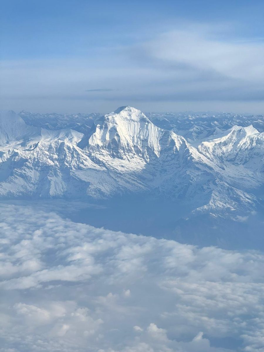 Snow-covered Himalayan peaks above the clouds, seen from a plane